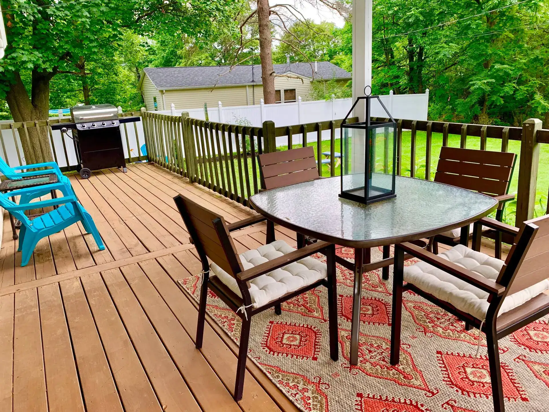 Wooden deck with an outdoor dining table, chairs, and grill